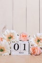 Happy May Day white block wood calendar decorated with spring flowers on wood table.