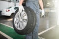 Close up of man mechanic carrying a tire in tire service Royalty Free Stock Photo