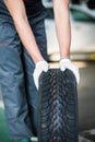 Close up of man mechanic carrying a tire in tire service Royalty Free Stock Photo