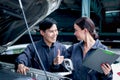 Happy mechanic man and woman mechanic in uniform discussing while working together with engine vehicle at garage, two auto Royalty Free Stock Photo