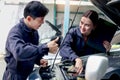 Happy mechanic man and woman mechanic in uniform discussing while working together with engine vehicle at garage, two auto Royalty Free Stock Photo