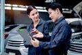 Happy mechanic man and woman mechanic in uniform discussing while working together with engine vehicle at garage, two auto Royalty Free Stock Photo