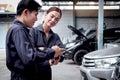 Happy mechanic man and woman mechanic in uniform discussing while working together with engine vehicle at garage, two auto Royalty Free Stock Photo