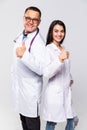 Happy medic workers. Portrait of two doctors in white coats and glasses showing thumb-up against white background Royalty Free Stock Photo