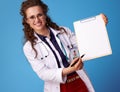 Happy medical doctor woman giving clipboard to sign on blue Royalty Free Stock Photo