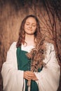 Happy medieval young woman in historical female costume with reeds bouquet