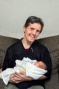 Happy Man With Downs Syndrome and Fake Teeth Holds Newborn Infant