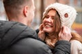 Happy man puts on a winter hat for his woman. The guy in love takes care of the girl