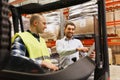 Happy men with tablet pc and forklift at warehouse Royalty Free Stock Photo