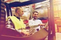 Happy men with tablet pc and forklift at warehouse Royalty Free Stock Photo