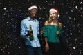 Joyful couple congratulating on christmas with champagne at black background