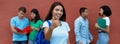 Happy mexican female student showing thumb up with group of multiethnic students