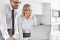 Happy mid adult business couple using laptop at kitchen counter Royalty Free Stock Photo