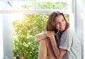 Happy mid adult woman sitting by window at home Royalty Free Stock Photo