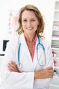 Happy Mid age female doctor in consulting room Royalty Free Stock Photo