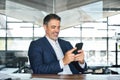 Happy mid aged business man ceo executive using mobile phone at work in office. Royalty Free Stock Photo