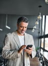 Happy mid aged business man holding cell using mobile phone in office. Royalty Free Stock Photo