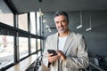 Happy mid aged business man holding mobile cell phone in office. Portrait Royalty Free Stock Photo