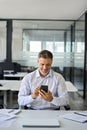 Happy mid aged business man manager using cell phone at work in office. Royalty Free Stock Photo
