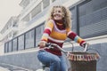 Happy middle age active woman riding a bike in the city wearing colorful sweater. Green transport mode and outdoor urban leisure