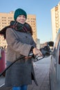 Happy middle age adult woman holding fuel pump by car at self-service gas station Royalty Free Stock Photo