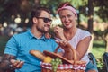 Attractive middle age couple during dating, enjoying a picnic on a bench in the city park. Royalty Free Stock Photo