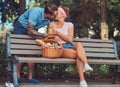 Attractive middle age couple during dating, enjoying a picnic on a bench in the city park. Royalty Free Stock Photo