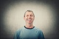Happy middle age man smiling wearing casual t-shirt isolated over grey wall background. Portrait of cheerful male senior laughing
