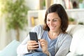 Happy middle age woman checking phone on a couch at home Royalty Free Stock Photo