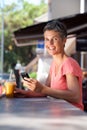 Happy middle age woman sitting outside with mobile phone and drink Royalty Free Stock Photo