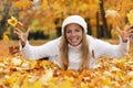 Happy middle age woman throwing yellow autumn leaves