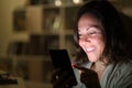 Happy middle age woman using phone at night at home Royalty Free Stock Photo