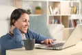 Happy middle age woman watching video on laptop at home