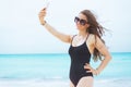 Happy middle age woman on white beach taking selfie with phone Royalty Free Stock Photo