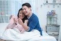 Happy middle aged Asian couple looking result at pregnancy test together on bed at home. Wife surprise husband with positive Royalty Free Stock Photo