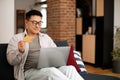 Happy middle aged asian man using credit card for online shopping, sitting on sofa with laptop, free space Royalty Free Stock Photo