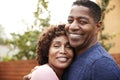 Happy middle aged African American couple embracing smile to camera, close up