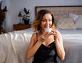 Happy middle-aged blond woman holding a cup of tea or coffee looking at the camera in cozy home Royalty Free Stock Photo