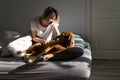 Happy middle-aged blonde lady plays with sleepy Vizsla dog on bed in sunny morning Royalty Free Stock Photo