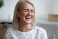 Happy middle aged blonde woman laughing at funny joke.