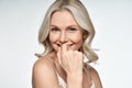 Happy middle aged blonde woman looking at camera advertising face skin care.