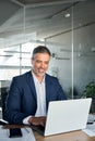 Happy middle aged business man ceo wearing suit sitting in office using laptop. Royalty Free Stock Photo