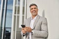 Happy middle aged business man using mobile phone looking away outdoors. Royalty Free Stock Photo