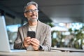 Happy middle aged business man using phone sitting outside office looking away. Royalty Free Stock Photo