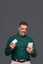 Happy middle aged business man holding mobile phone and credit card mockup. Royalty Free Stock Photo