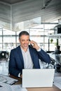 Happy middle-aged business man making phone call using laptop in office. Royalty Free Stock Photo
