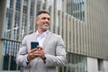 Happy middle aged business man using mobile cell phone looking away outdoors. Royalty Free Stock Photo