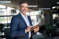 Happy middle aged business man wearing suit using digital tablet in office. Royalty Free Stock Photo