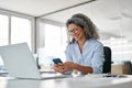 Happy middle aged business woman holding phone using cellphone in office. Royalty Free Stock Photo