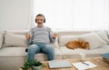 Happy middle-aged Caucasian man closing his eyes while enjoying song listening to it in headphones and his lovely chihuahua dog Royalty Free Stock Photo